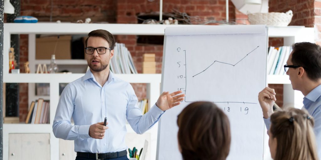 Serious confident business coach gives presentation on flipchart training workers